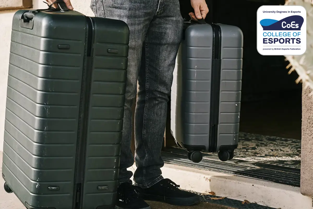 Image depicts a man holding two suitcases walking out of a front door. This image is for the University Essentials Article.