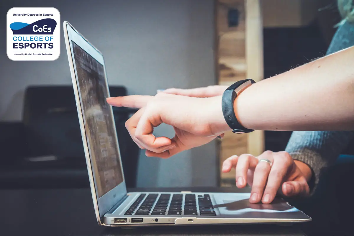 Image depicts a person with a laptop pointing with their left hand to the laptop screen. In the top left is the University Campus of Esports logo. This is the thumbnail image of the Student Finance guide article.